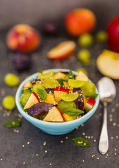 Delicious and healthy fresh fruit salad in bowl on dark stone background.