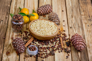 Cedar nuts and cones on wooden table. Tangerines, rolls of cinnamon