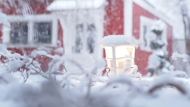 heavy snowfall with red house defocused in the background