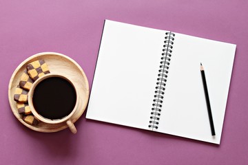 Still life, business, office supplies or education concept : Top view of working desk with blank notebook with pencil, cookies and coffee cup on color background