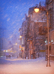 Winter story. Night snowfall on the street of the city.
