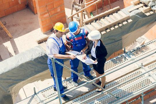 Arbeiter und Architektin besprechen Pl&auml;ne auf Baustelle
