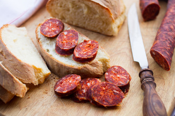 knife,  fresh bread and sausage on the table
