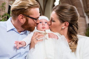 Junge Eltern küssen ihr Baby gleichzeitig nach der Taufe 