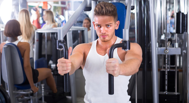Young man using fly machine in gym.