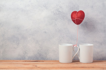 Valentines day concept with coffee cups and heart shape balloon over rustic background