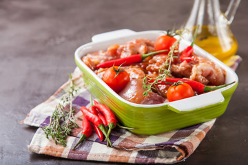 pieces of chicken meat in tomato sauce in shape for roasting on a table, selective focus, copy space