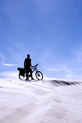 Fototapeta premium Traveling man on a bicycle in the desert.