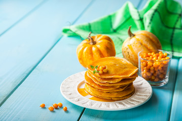 pumpkin pancakes with syrup in a plate on a table, selective focus, copy space