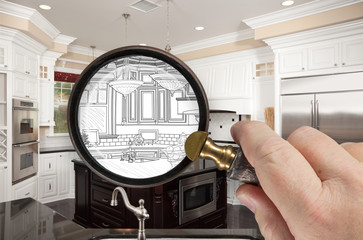 Hand Holding Magnifying Glass Revealing Custom Kitchen Design Drawing and Photo Combination.
