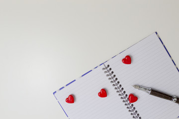 Open notebook with red hearts and pen. Top view. Copy space for text