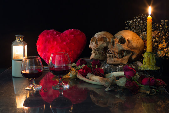 Two skulls, with bone and dry flowers in valentines night