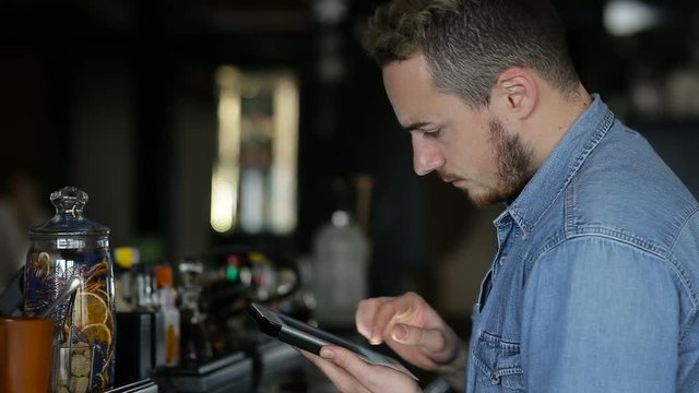 A man uses tablet while sitting at the bar