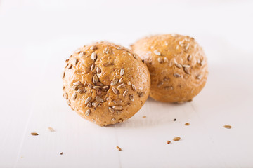 Four buns with seeds on a light wooden background, top view