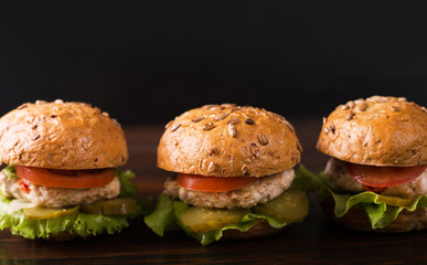 Three burgers on a dark wooden table