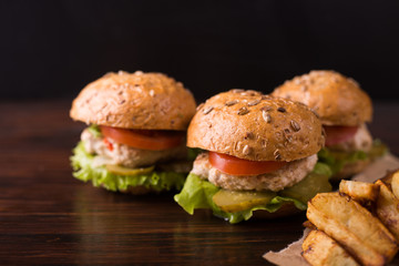 Three burgers on a dark wooden table