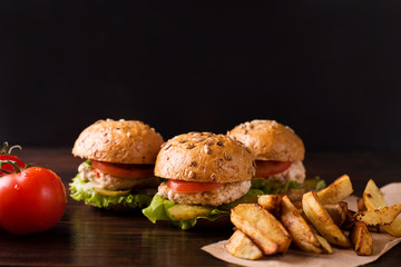 Three burgers on a dark wooden table