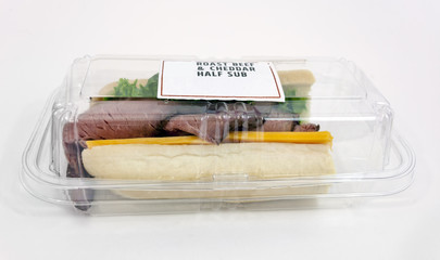 Roast beef, cheese and lettuce sandwich in plastic deli container. Isolated.