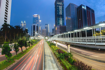 Light trail of vehicle traffic in Jakarta main road, Sudirman Street,  Jakarta. Also showing row of beautiful pedestrian bridge in the middle of the road. Urban Skyline, Building Exterior