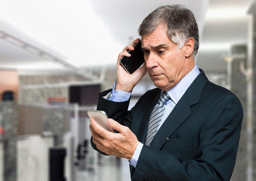 Worried businessman talking at the phone while looking to another phone