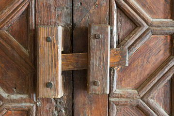 Closeup of a wooden aged latch over an ornate wooden door