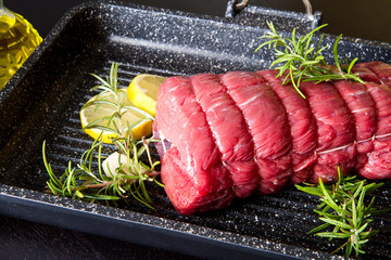 roast of beef with rosemary on plate pot on black