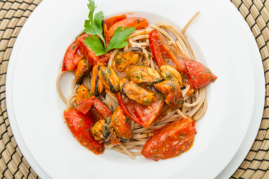 white dish with spaghetti, mussel and tomatoes