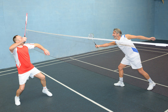 Men reaching out during badminton game