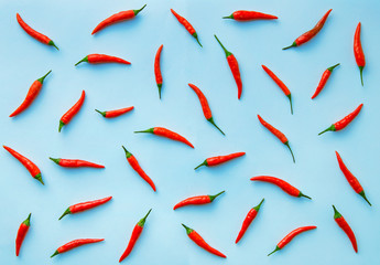 Flat lay red chili peppers pattern on blue background. Top view