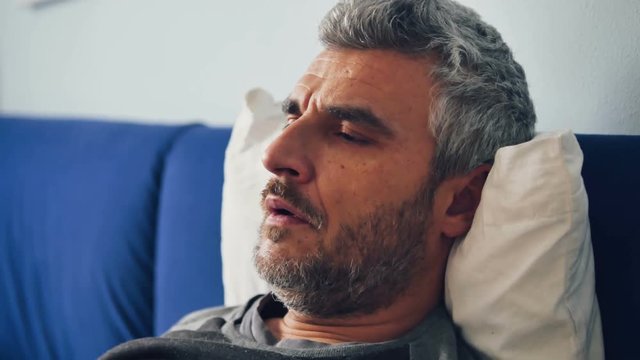 sick man on bed with breathing problems coughing using aerosol nubulizer inhaler