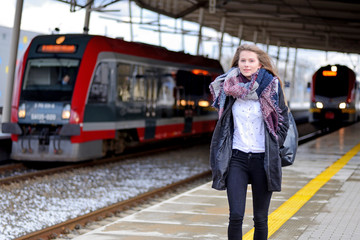 Young woman on a train station. - obrazy, fototapety, plakaty
