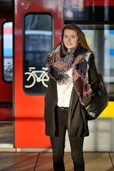 Young woman on a train station. - obrazy, fototapety, plakaty