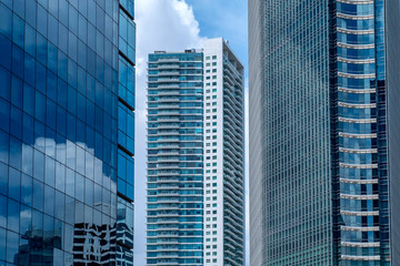 Skyscraper building in between another buildings, also show glass window on skyscraper, showing reflection of sky and building in Jakarta, Indonesia