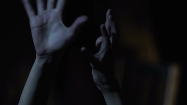 Hands of drug addict person stretching out, convulsing, psychopath in darkness