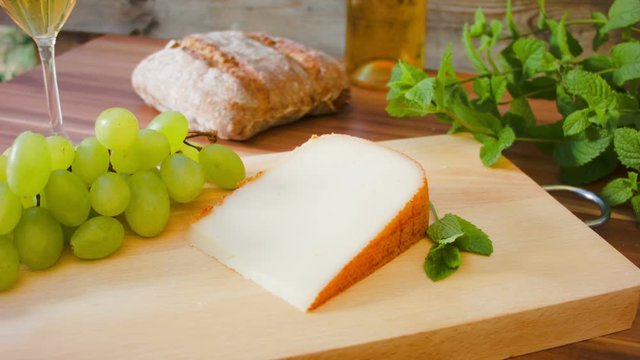 movement of the camera around of Hard cheese with white wine. grapes and bread