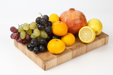 different fruits on a wooden board on a white background