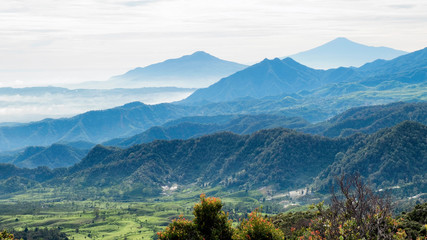 Aerial view of large area of forest, followed by misty hill and mountain, beautifully layered, seen from Tangkuban Perahu Summit,  Subang, Indonesia