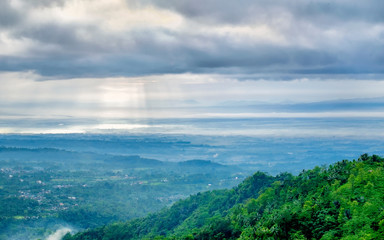 Majestic sun beam or god rays hitting the ground and forest, captured from the top. Captured from  Tranggulasih hill, Banyumas, Indonesia