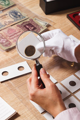 Woman looks at the coin through a magnifying glass