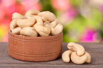 cashew nuts in a wooden bowl on the board with  blurred garden background