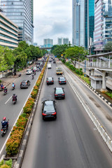 Fototapeta na wymiar Photo of big road in Jakarta and its traffic, consist of car and motorcycle, with skyscraper buildings in the both side of the road. Captured in Rasuna Said Street, Indonesia.