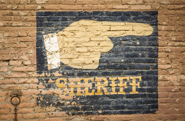 a sign indicating the location of the Sheriff painted on a wall 