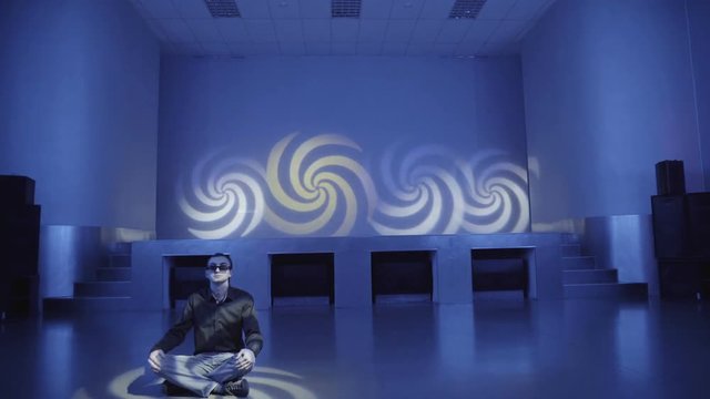 Hypnotized man in sunglasses sitting in Lotus posture