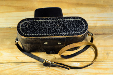 Old soviet rangefinder camera in leather case ona wooden table