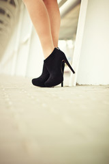 Beautiful female legs in black suede shoes with pavement in the