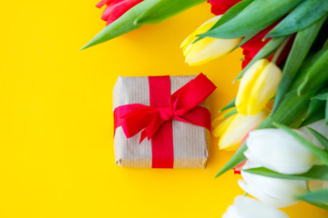 Multicolored tulips bouquet and gift box on yellow background