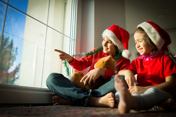 Two cute boys brothers on window waiting for Santa and New Year