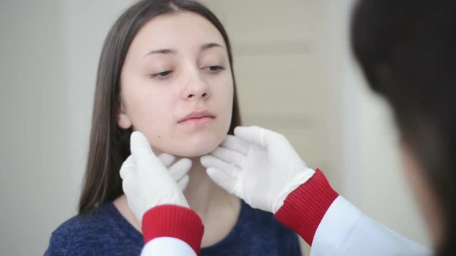 doctor is examining female patient's injured neck while working in his office