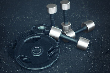 Weight plates and dumbbells on floor in gym