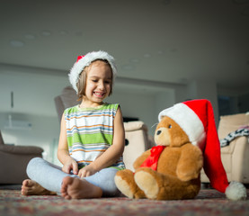 Little boy with his cute Teddy bear waiting for Santa Claus at h